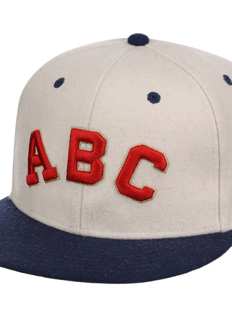 The Ebbets Field Atlanta Black Crackers NLB Ballpark Fitted Ballcap is beige with a dark blue brim and top button, featuring bold red “ABC” letters on the front.