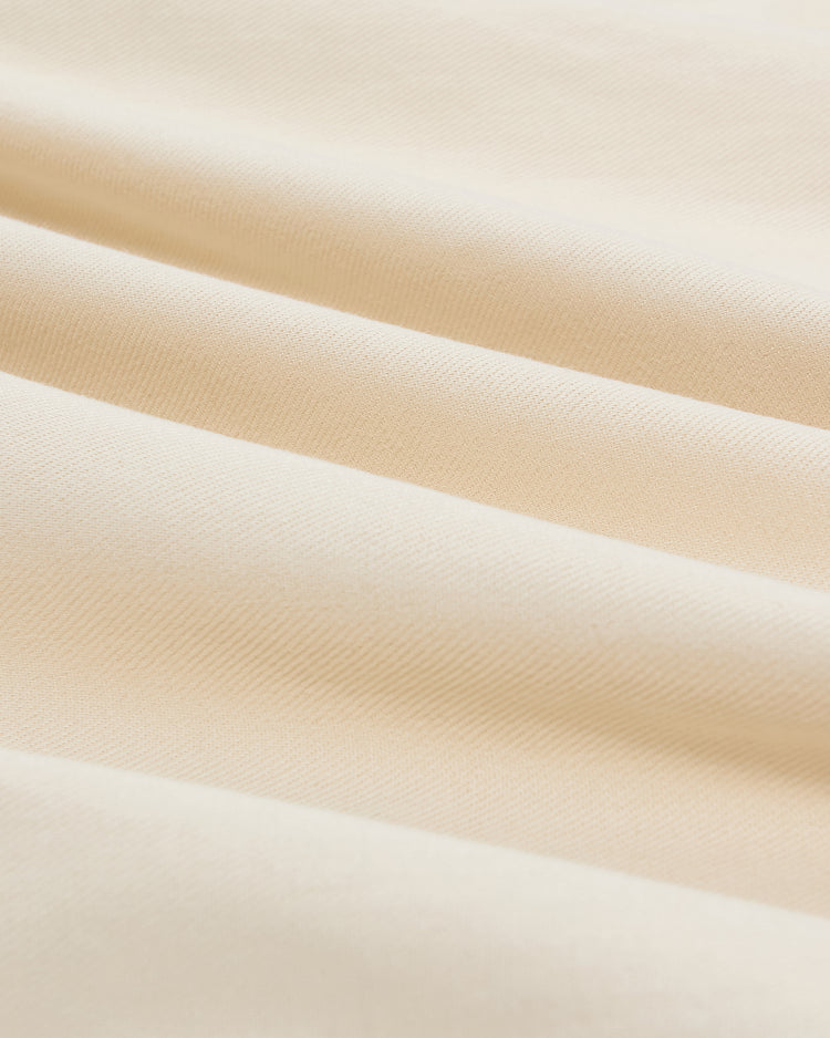 Close-up of folds in the cream-colored cotton twill fabric of a San Francisco Sea Lions Cotton Twill Baseball Jersey, featuring a diagonal weave.