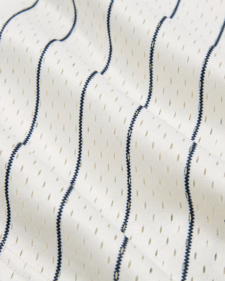 Close-up of white textured mesh fabric with small perforations and parallel dark blue stitched lines from the Ebbets Field San Francisco Seals 1940 Mesh Baseball Jersey, evoking the vintage Pacific Coast League uniform. Fabric appears slightly wrinkled or folded.