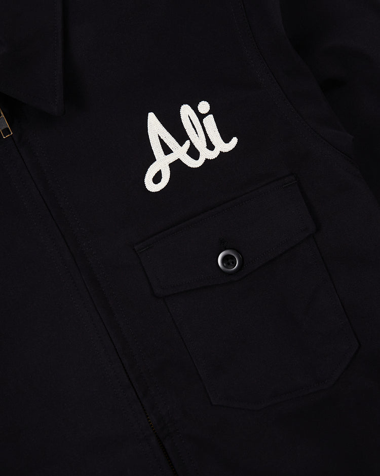 A close-up of the black Ebbets Field Muhammad Ali Training Camp Cotton Grounds Crew Jacket with a buttoned pocket and 