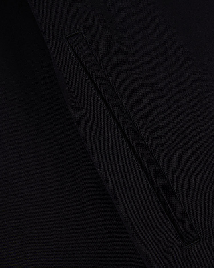 Close-up of a black cotton fabric with a neatly stitched vertical slit pocket on the Muhammad Ali Training Camp Cotton Grounds Crew Jacket by Ebbets Field, highlighting the texture and refined detail of the material.