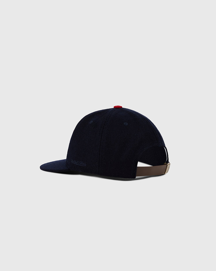 A dark navy Ebbets Field Minnesota Twin 1961 MLB Authentic Wool Ballcap viewed from the back, with a curved brim, red top button, and adjustable tan strap with metal clasp. Plain light gray background.