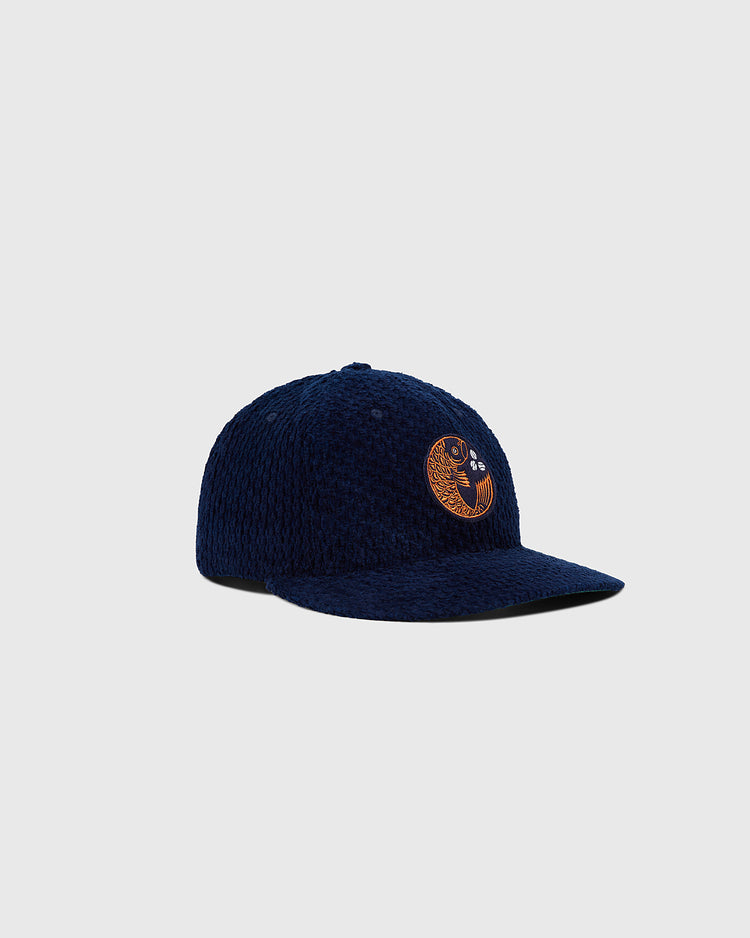 The Ebbets Field Hiroshima Carp Japanese Indigo Corduroy Ballcap is a navy blue textured hat with an orange embroidered circular face logo, shown on a plain light gray background.