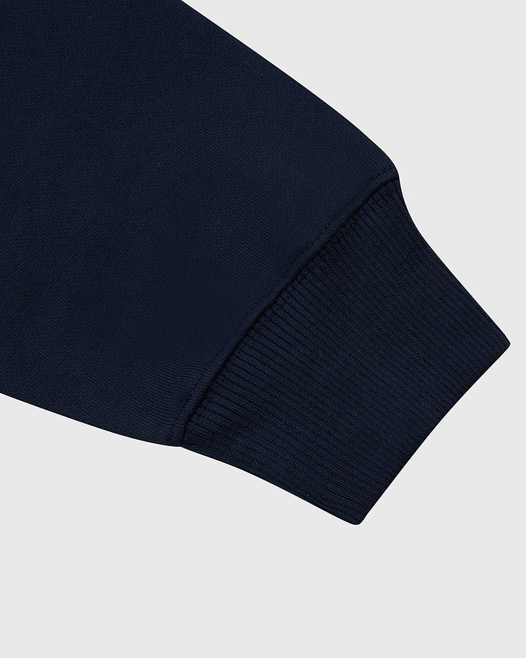 Close-up of the Ebbets Field USA 1960 Heavyweight Cotton Terry Pullover Hoodie in navy blue, highlighting its ribbed cuff and vintage hockey-inspired design against a plain light gray background.