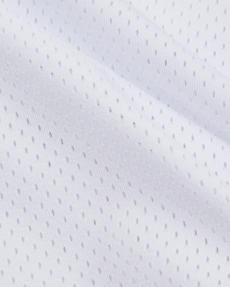 Close-up of the Harvard Vintage Mesh Football Jersey by Ebbets Field, featuring white athletic mesh with small, evenly spaced holes for breathability. Gently folded fabric and soft shadows evoke a classic throwback jersey feel.