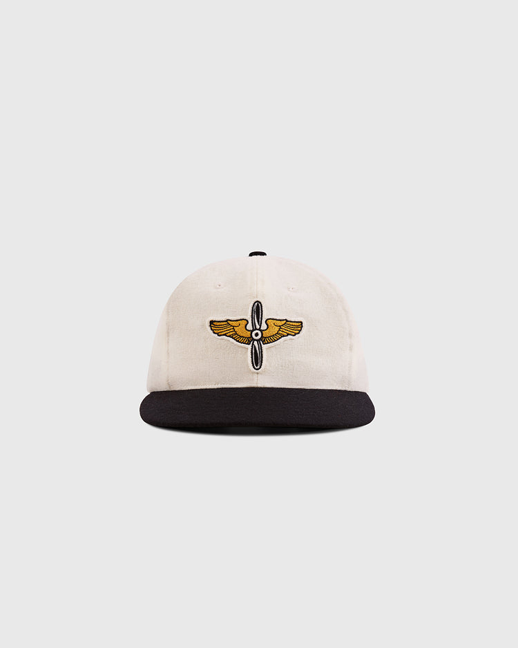 The Ebbets Field Mystery Caps of Mexico – Aviacion 1917 Authentic Wool Ballcap features a cream crown, black brim, and an embroidered gold and black winged emblem, celebrating Mexican baseball history against a white backdrop.