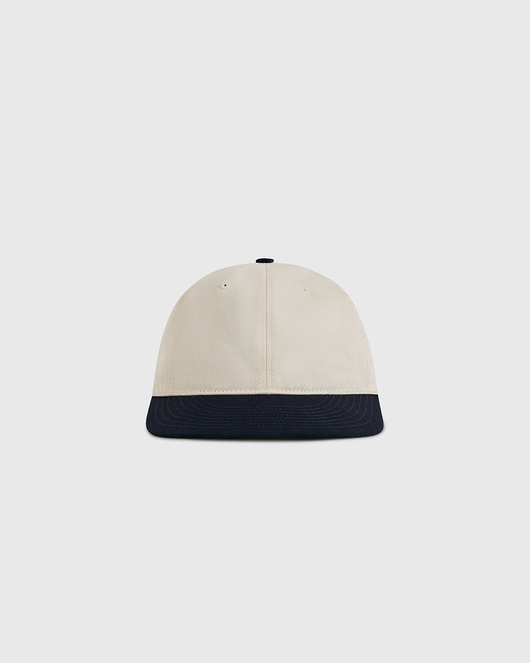The Ebbets Field Natural and Navy Cotton Twill Ballcap is shown from the front, featuring a cream-colored crown and a navy brim against a plain light background.