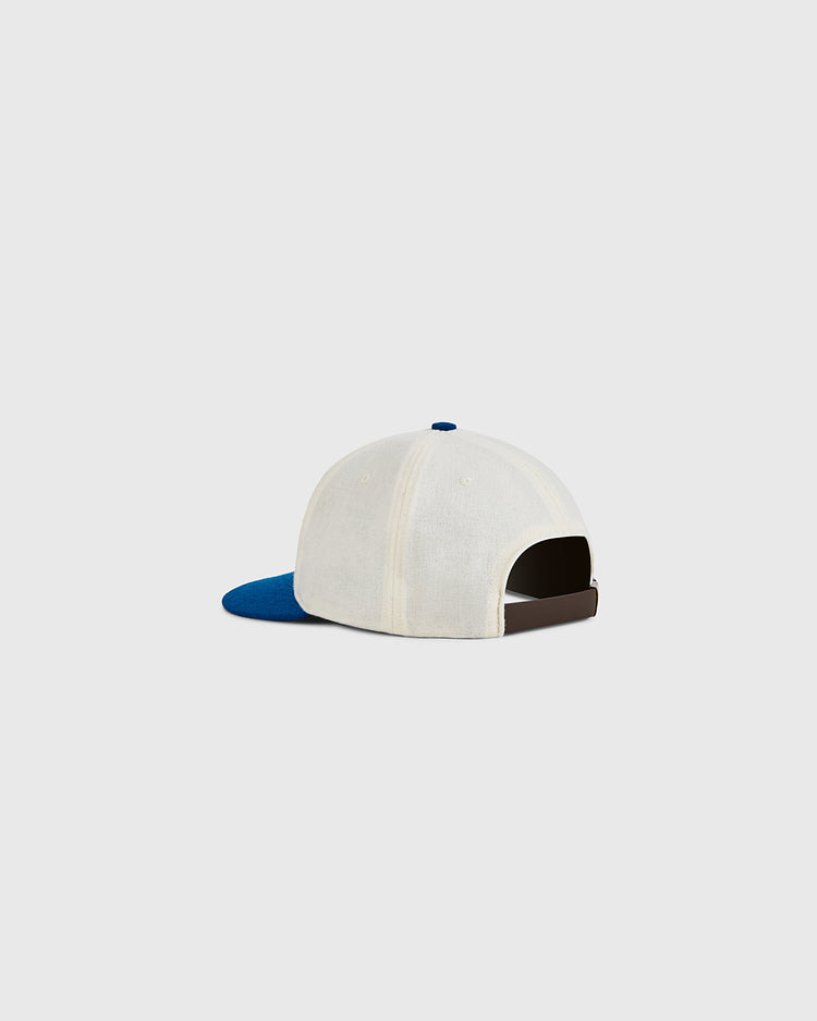 The Ebbets Field USA 1960 Wool Ballcap, in beige with a blue brim, is displayed from the back. This Olympic hockey hat has an adjustable strap and top button, set against a plain light gray background.