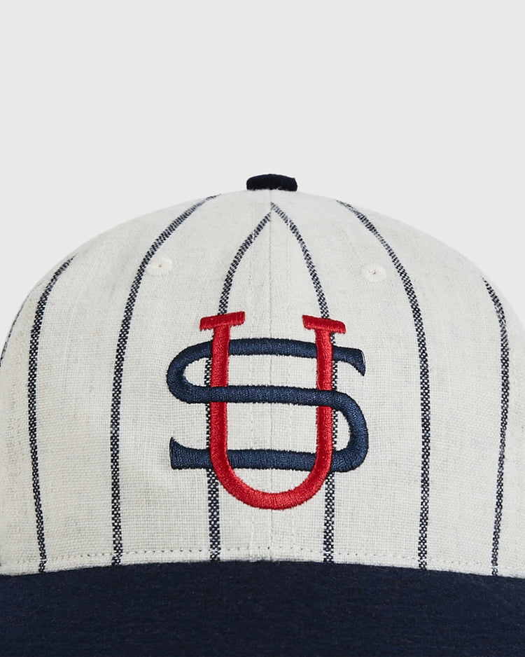 The Ebbets Field US Tour of Japan 1934 Authentic Wool Ballcap features white wool with thin black pinstripes, a navy brim, and red-and-blue S and U embroidery—a classic design inspired by the 1934 tour collection.
