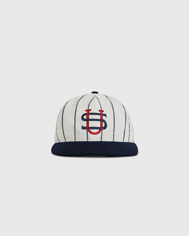 The Ebbets Field US Tour Of Japan 1934 Authentic Wool Ballcap features white wool with thin navy stripes, a navy brim, and an overlapping red and navy U-S logo embroidered on the front, inspired by the historic 1934 tour.