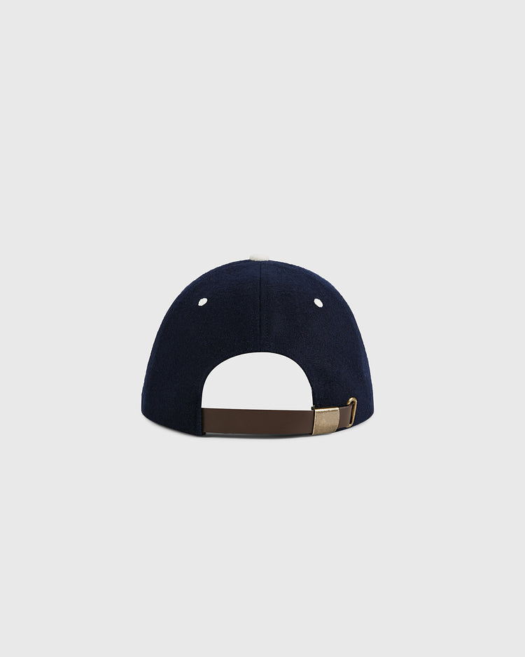 The Ebbets Field USA Stars and Bars Shield Wool Ballcap, shown from the back on a light gray background, features navy wool fabric, a brown adjustable strap with gold buckle, and is proudly made in the USA.