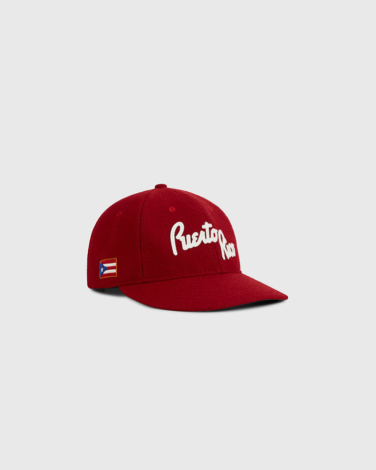 The Ebbets Field Puerto Rico 1958 National Team Wool Ballcap features red wool, white Puerto Rico script on the front, and a small Puerto Rican flag patch on the side, shown against a plain light gray background.