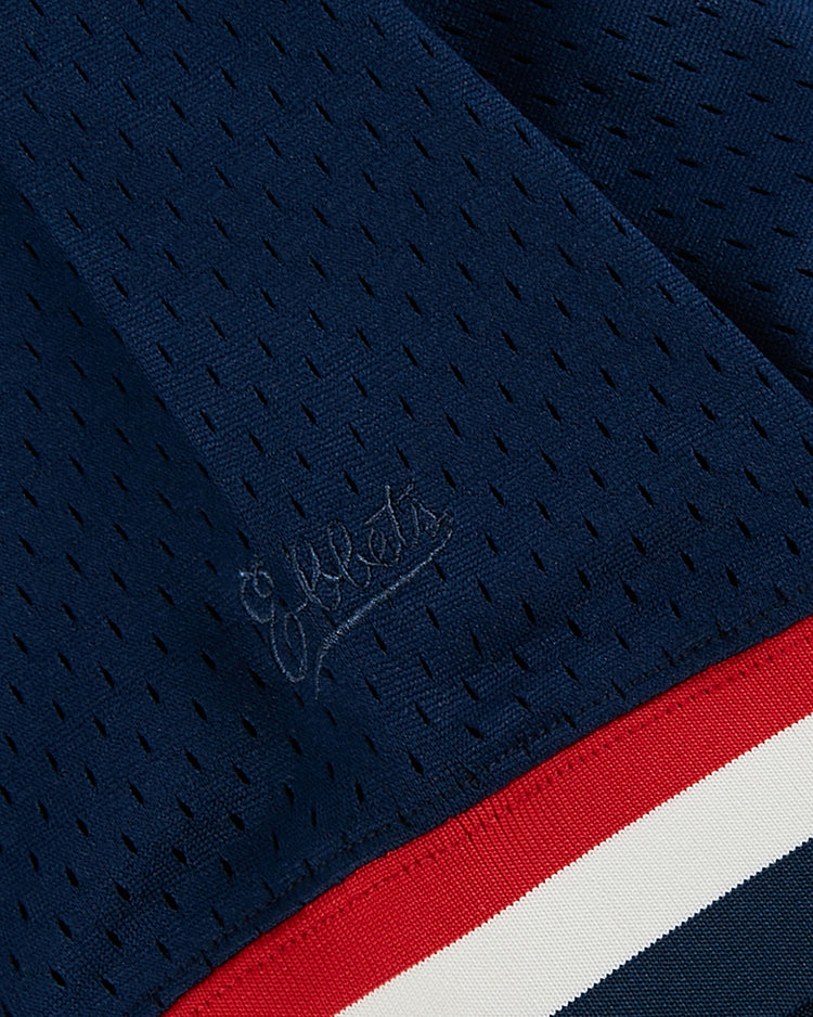 Close-up of the USA National Team Mesh V-Neck Jersey by Ebbets Field, featuring navy blue mesh fabric with subtle matching script embroidery and a red-and-white stripe at the hem, inspired by vintage baseball jersey details.