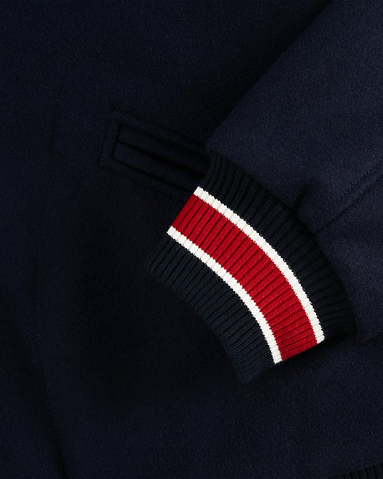 Close-up of the Ebbets Field USA 1960 All-Wool Varsity Jacket sleeve with a ribbed cuff in red, white, and navy stripes. The wool texture and side pocket of this vintage-inspired jacket are also visible.