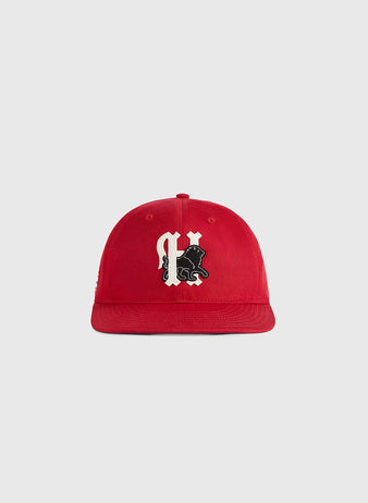 The Habana Leones Cotton Twill Ballcap by Ebbets Field, featuring a red cotton twill design and a black-and-white gothic C with a lion, is centered on a plain light gray background.