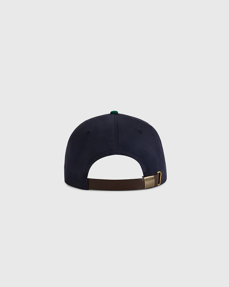 The Ebbets Field University of Notre Dame Shamrock Cotton Twill Ballcap is shown from the back, featuring a brown adjustable strap with a brass buckle, set against a plain light gray background.