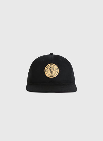 The Ebbets Field Guinness Extra Stout Patch Cotton Twill Ballcap is a black flat-brim cap with a round beige patch on the front, featuring 