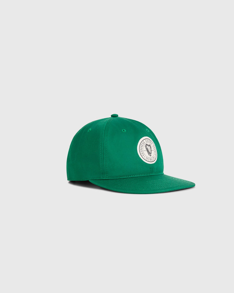 The Ebbets Field Guinness Extra Stout Patch Cotton Twill Ballcap is green with a white circular patch and emblem on the front, shown against a plain light gray background for a classic look.