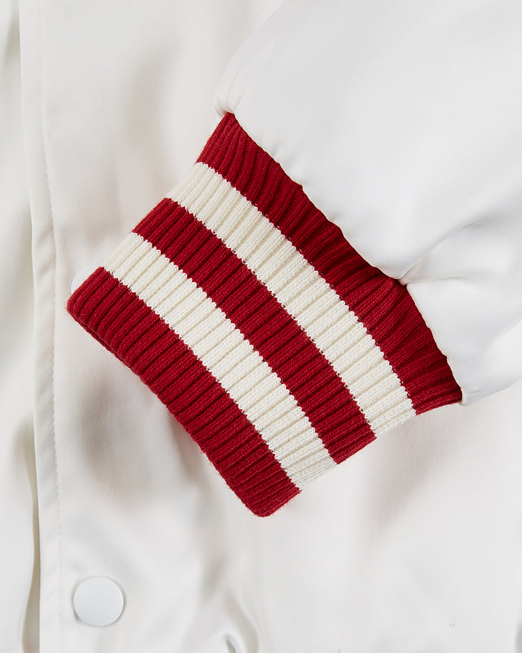 Close-up of the Diablos Rojos del Mexico Satin Varsity Jacket by Ebbets Field, showing a white sleeve with a red and white ribbed cuff and a visible white snap button, highlighting its classic satin varsity style.