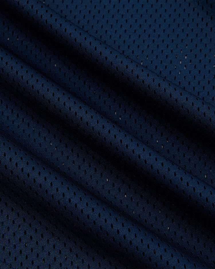 Close-up of Ebbets Field’s University of Notre Dame V-Neck Mesh Jersey in dark blue, featuring small black polka dots on lightly textured fabric, softly folded to highlight its vintage-inspired details.