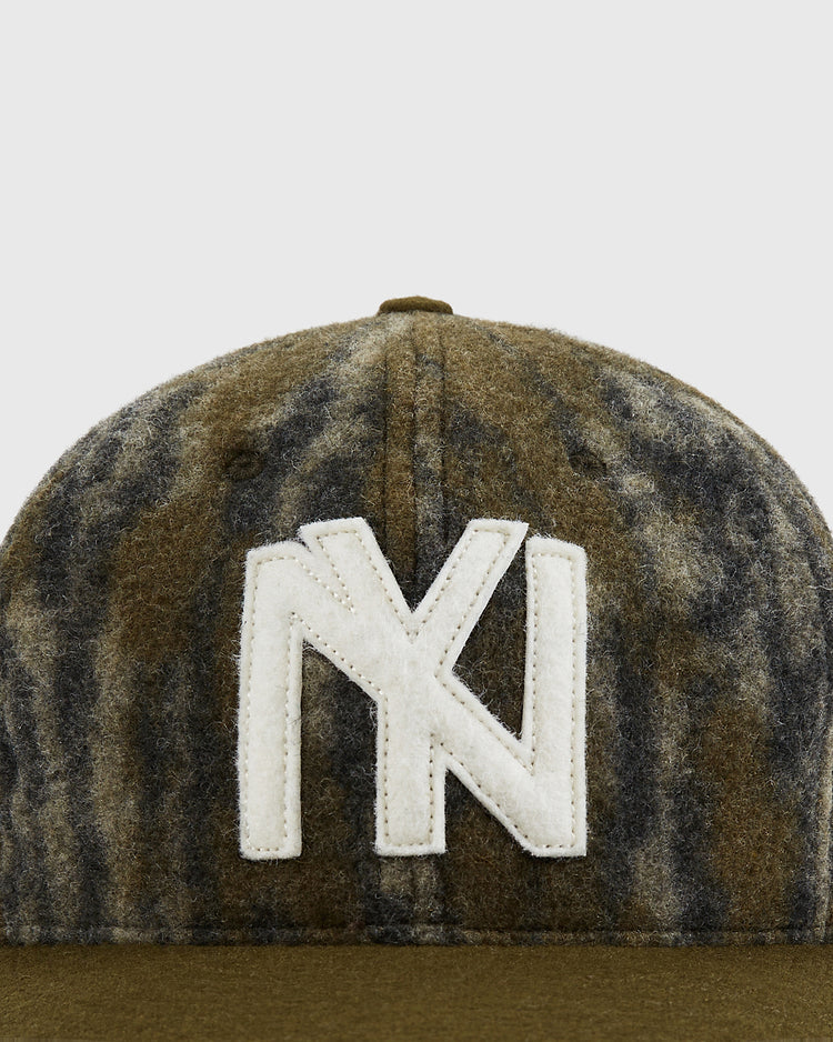 A close-up of the Mossy Oak x Ebbets Field 1935 Brooklyn Eagles Ballcap by Ebbets Field, featuring brown and gray camo with a large white overlapping N and Y logo stitched on the front.