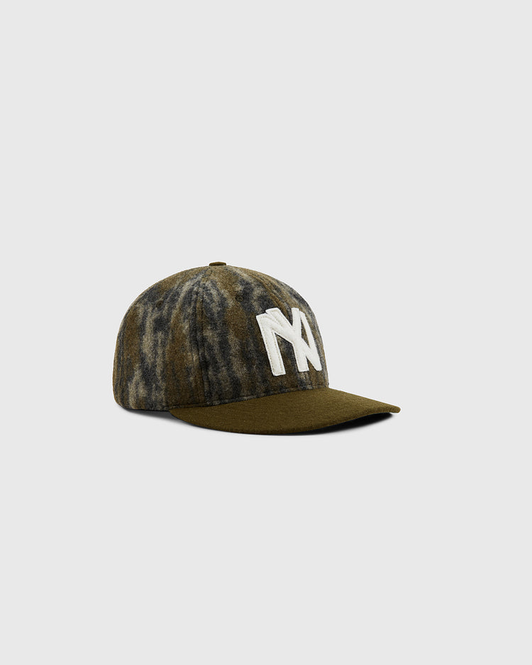 The Ebbets Field Mossy Oak x Ebbets Field 1935 Brooklyn Eagles Ballcap features a green and brown camo design with a bold white NY logo, shown on a plain light gray background.