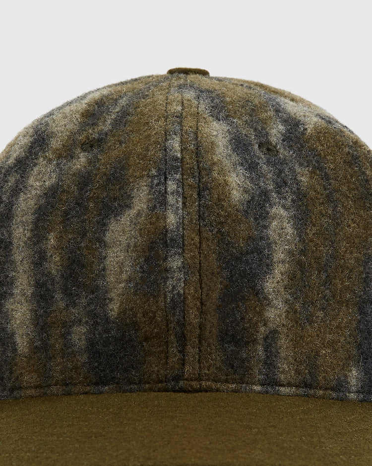 Close-up of the front panel and brim of the Ebbets Field Mossy Oak x Ebbets Field Blank Ballcap, showcasing its wool blend construction and Mossy Oak Bottomland camo pattern in brown, green, and gray against a light background.