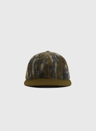 A front-facing view of the Ebbets Field Mossy Oak x Ebbets Field Blank Ballcap, featuring a Mossy Oak Bottomland camo pattern in green, brown, and gray, displayed against a plain light gray background.