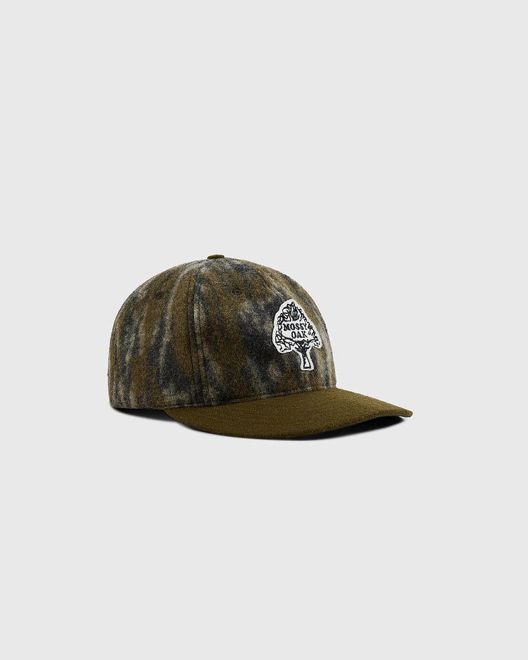 The Mossy Oak x Ebbets Field Vintage Tree Logo Ballcap by Ebbets Field features a brown and gray tie-dye design, flat brim, and a white embroidered patch with a tree and 