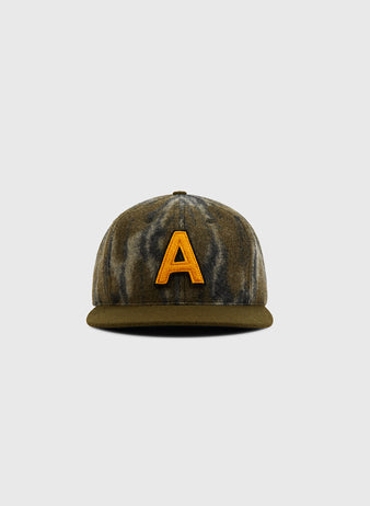 The Ebbets Field Mossy Oak x Ebbets Field 1957 Army Ballcap features a green and brown Bottomland camo pattern with a bold yellow 