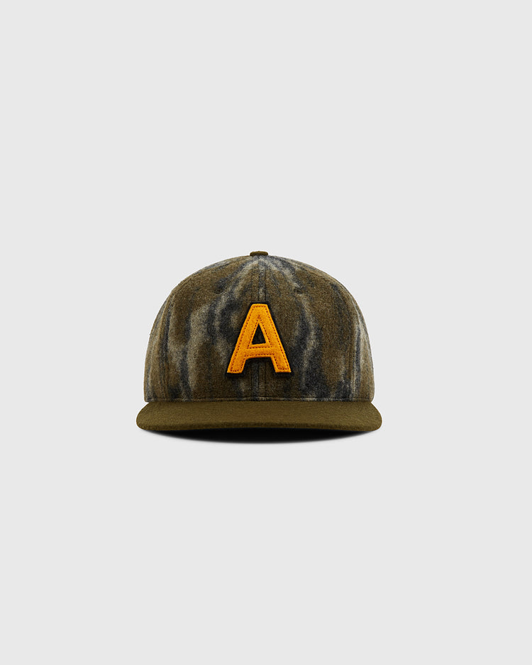 The Ebbets Field Mossy Oak x Ebbets Field 1957 Army Ballcap features a green and brown Bottomland camo pattern with a bold yellow 