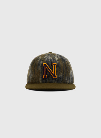 The Ebbets Field Mossy Oak x Ebbets Field 1947 Navy Ballcap features a brown and gray marbled camo pattern, a bold yellow and black 