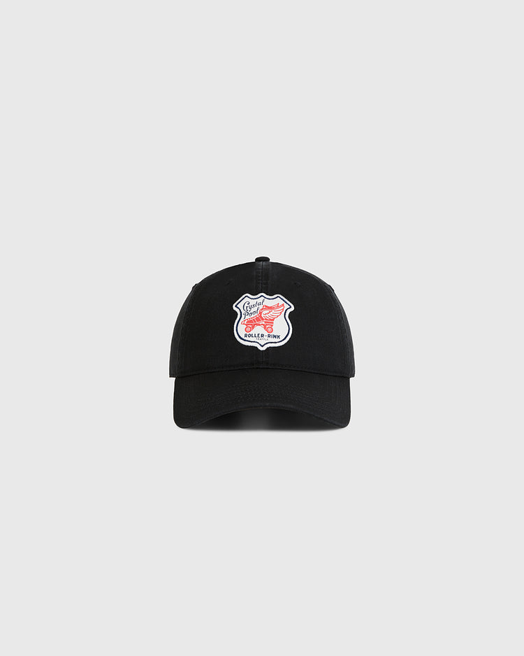 The Ebbets Field Seattle Crystal Pool Roller Rink Washed Cotton Ballcap is a black vintage-style cap with a white patch featuring red text and design, inspired by Seattle’s Crystal Pool roller rink, shown on a plain light gray background.