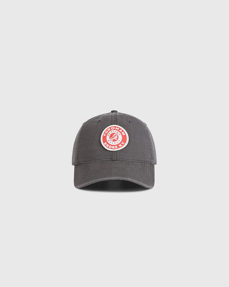 The Ebbets Field Fordham Bronx Roller Rink Washed Cotton Ballcap, dark gray with a circular red and white GOODRYN BOOKS INC. patch on the front, is shown against a plain light gray background.