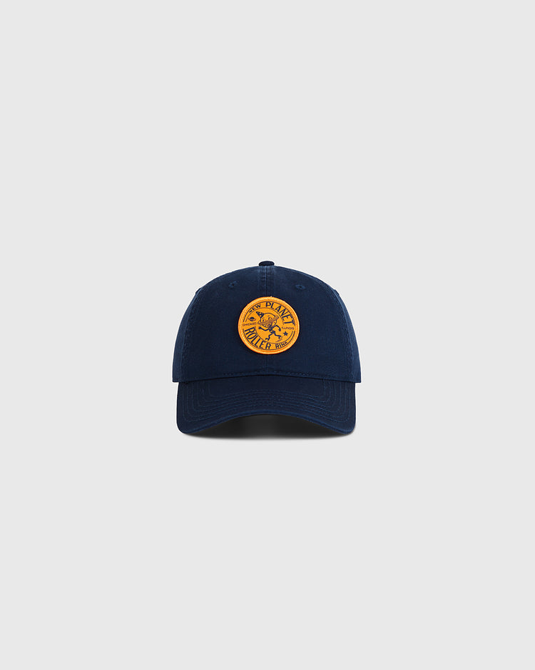 The Ebbets Field Chicago New Planet Roller Rink Washed Cotton Ballcap in navy features a round yellow patch with retro roller rink-inspired graphic and text, shown on a plain light gray background.