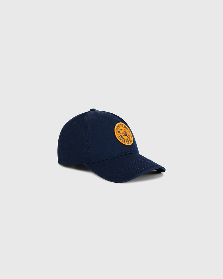The Ebbets Field Chicago New Planet Roller Rink Washed Cotton Ballcap features a curved brim and round yellow logo patch on navy cotton, bringing vintage roller rink style to any outfit. Displayed on a plain light gray background.