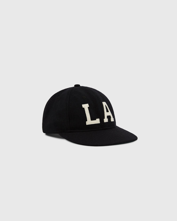 The EFF Los Angeles (PCL) 1949 Authentic Wool Ballcap in black features a curved brim and bold white LA letters, inspired by the Pacific Coast League, shown against a plain light gray background.