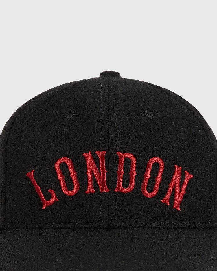 A close-up of the Ebbets Field London City Series Wool Ballcap: a black genuine wool hat with bold red 