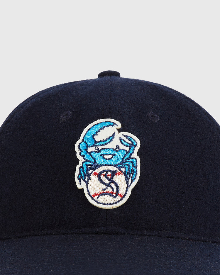 The Santurce Cangrejeros Crab Wool Ballcap by Ebbets Field is a navy blue wool cap featuring an embroidered crab holding a red-stitched baseball, inspired by Puerto Rican baseball and the iconic team.