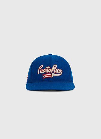 The Ebbets Field Puerto Rico 1972 National Team Wool Ballcap features “Puerto Rico” in white embroidery and a Puerto Rican flag on the front—a classic blue cap, ideal for collectors. Shown on a plain light gray background.