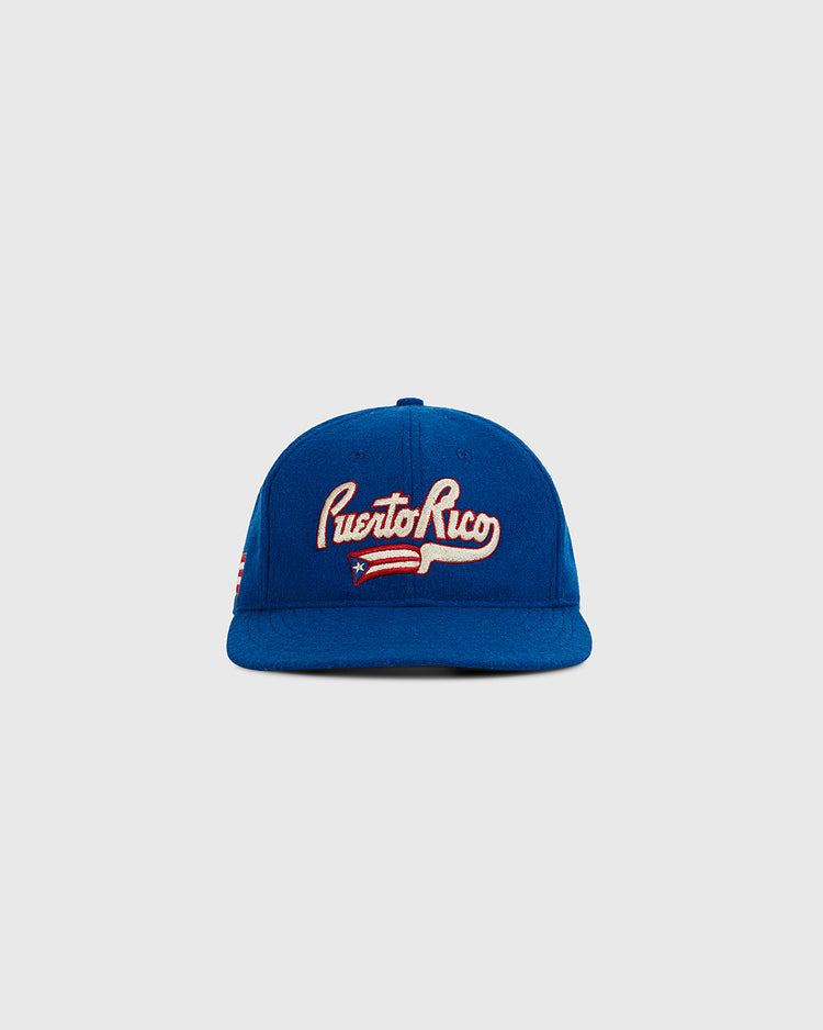 The Ebbets Field Puerto Rico 1972 National Team Wool Ballcap features “Puerto Rico” in white embroidery and a Puerto Rican flag on the front—a classic blue cap, ideal for collectors. Shown on a plain light gray background.