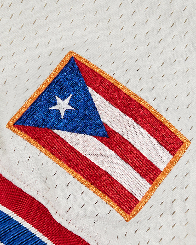 The Ebbets Field Puerto Rico 1972 National Team Mesh V-Neck Jersey features a sewn Puerto Rican flag patch on white mesh, inspired by the classic look of the 1972 national team.