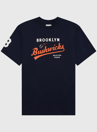 The Ebbets Field Brooklyn Bushwicks Short Sleeve Graphic Tee is a navy vintage-style shirt with “Brooklyn Bushwicks Dexter Park” text, a baseball graphic, and a white number 3 on the left sleeve.