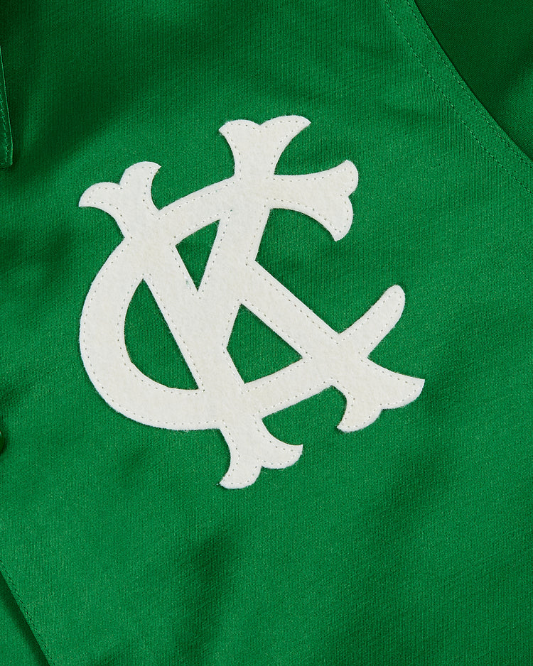 White interlocking KC letters logo stitched onto green fabric, from the EFF Kansas City Athletics 1963 Satin Windbreaker Jacket.