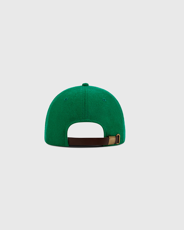 The Ebbets Field New York Cosmos Wool Ballcap is shown from the back, displaying an adjustable brown strap with a brass buckle. This green cap pays tribute to legends like Pelé. Background is light gray.
