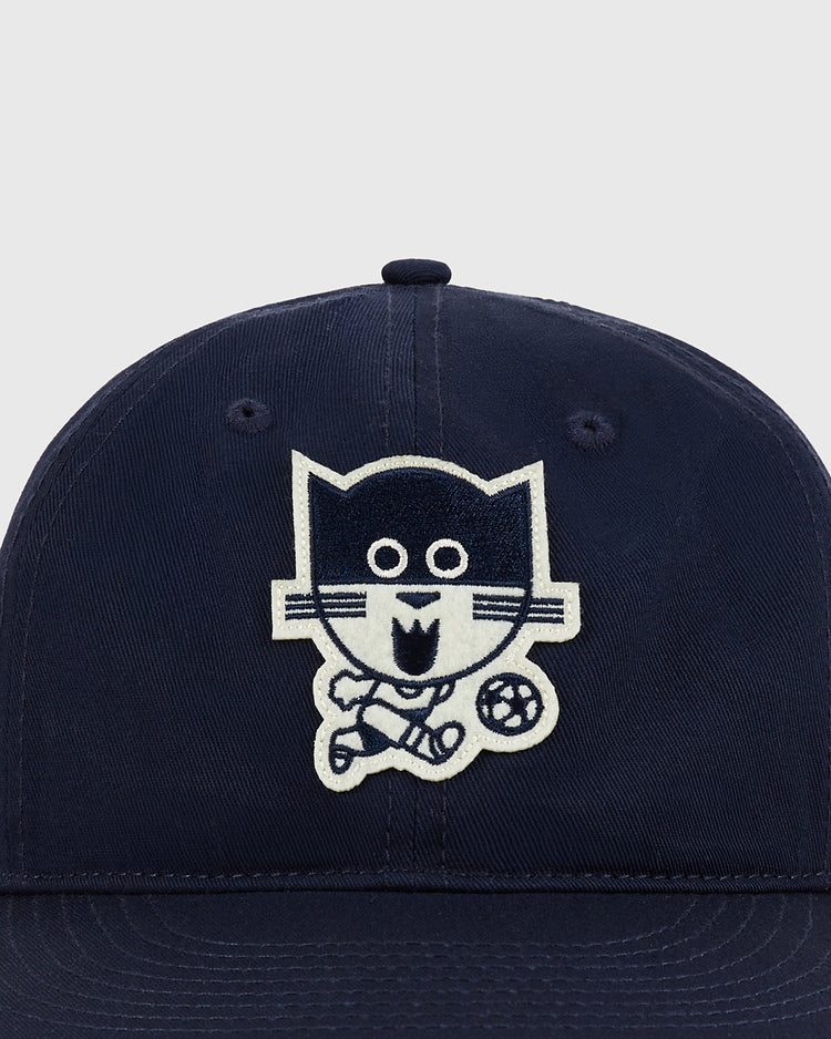 The Ebbets Field Chicago Cats Cotton Twill Ballcap is navy blue and features an embroidered cartoon cat playing soccer with a ball at its feet on the front center panel.