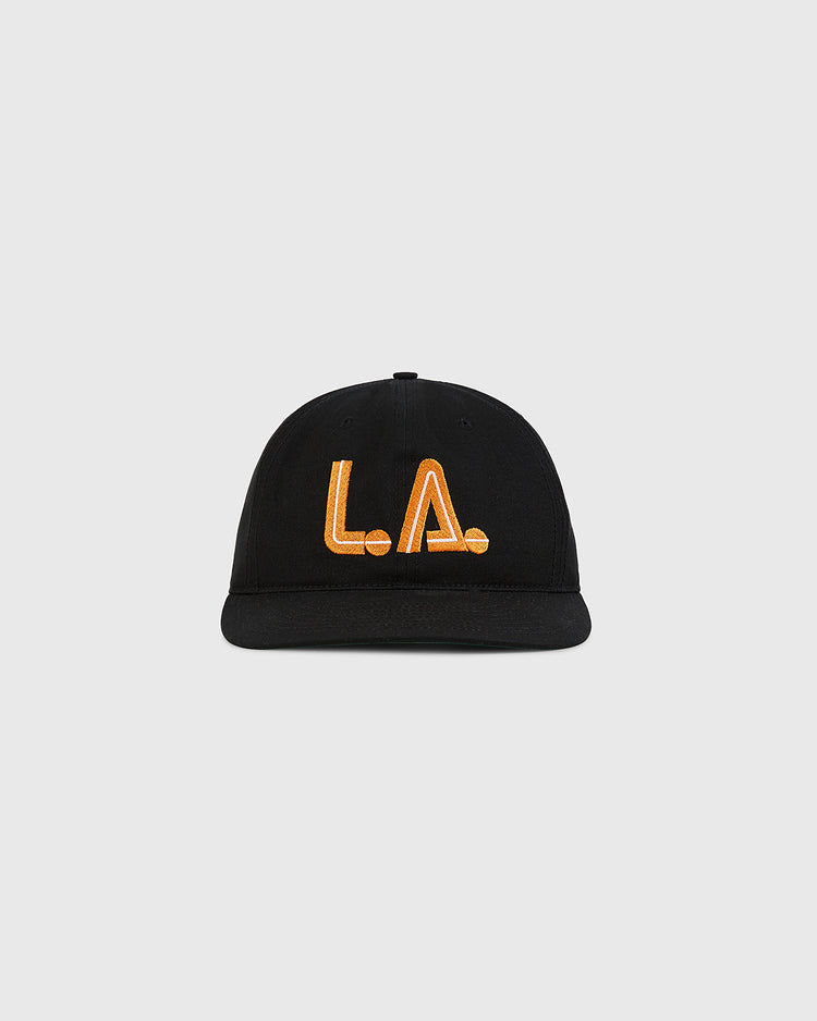 The Ebbets Field Los Angeles Aztecs Cotton Twill Ballcap in black features bold orange L.A. embroidery on the front, inspired by the historic NASL team, and is shown against a plain light gray background.