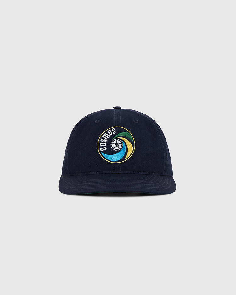 The Ebbets Field New York Cosmos Cotton Twill Ballcap in navy blue features an embroidered Cosmos logo with a stylized globe and colorful swoosh on the front, shown against a plain light gray background.