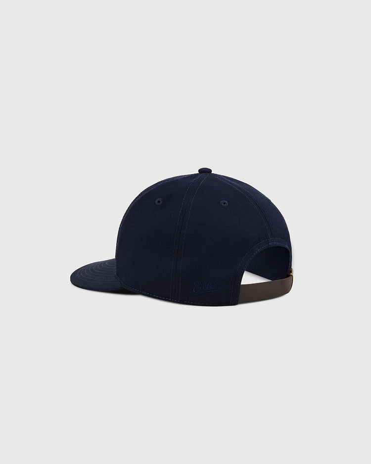 The Ebbets Field New York Cosmos Cotton Twill Ballcap, shown from the back left on a light gray background, features navy blue cotton twill, a curved brim, and an adjustable metal-buckle strap inspired by Pelé's iconic era.