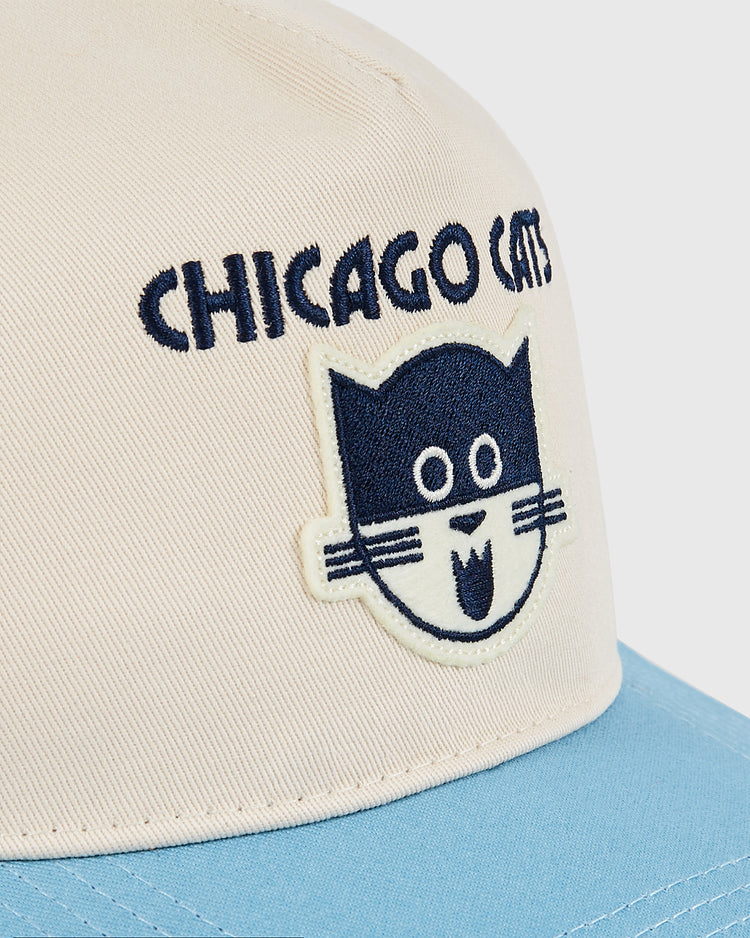A close-up of the Ebbets Field Chicago Cats A-Frame Cotton Twill Ballcap, featuring a beige front, light blue brim, embroidered cartoon cat face, and bold CHICAGO CATS text—a must-have for Chicago Cats or American Soccer League fans.
